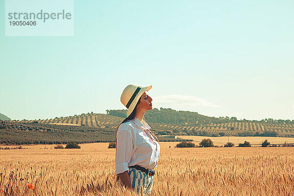 Ein Mädchen steht auf einem Weizenfeld und genießt einen sonnigen Tag in Spanien