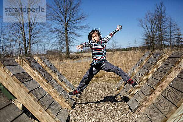 Ein konzentriertes Kind springt über eine Reihe von Holzrampen im Outdoor-Park