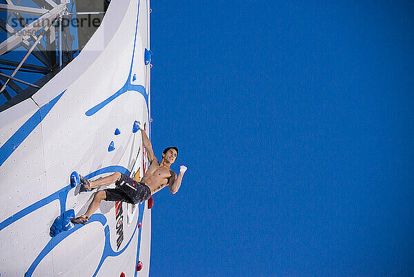 Mann klettert 55 Fuß hohe Wand. Mann klettert beim Psicobloc Masters auf eine 55 Fuß hohe Wand.