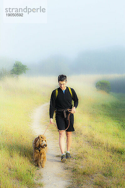 Erhöhte Vorderansicht einer Frau  die mit ihrem Hund spazieren geht.