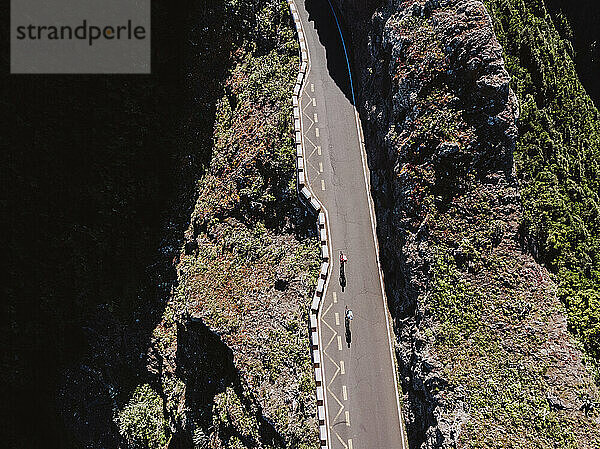 Luftaufnahme von zwei Radfahrern auf einer geraden Bergstraße