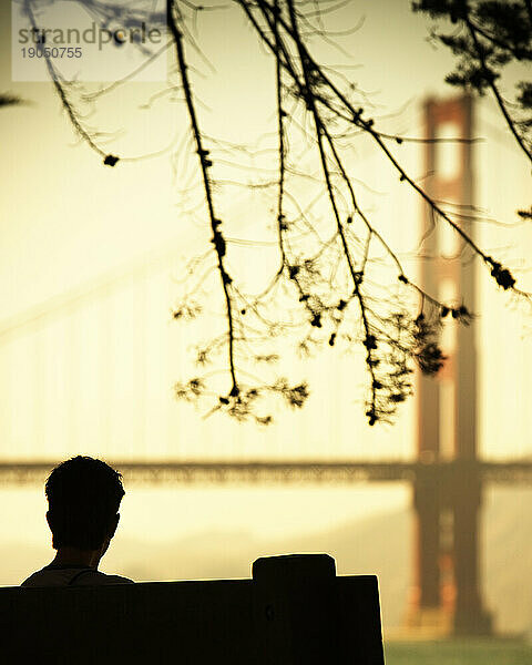 Rückansicht der Silhouette einer sitzenden Person  im Hintergrund die Golden Gate Bridge. San Francisco  Kalifornien.