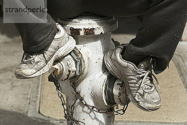 Eine Person sitzt auf einem Hydranten.