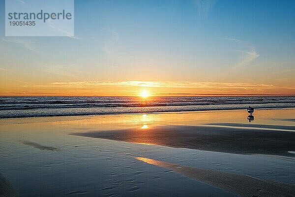 Sonnenuntergang über dem Atlantik mit der Silhouette eines Fotografen  der am Strand von Fonte da Telha  an der Costa da Caparica  Portugal  Bilder von der Brandung macht  Europa