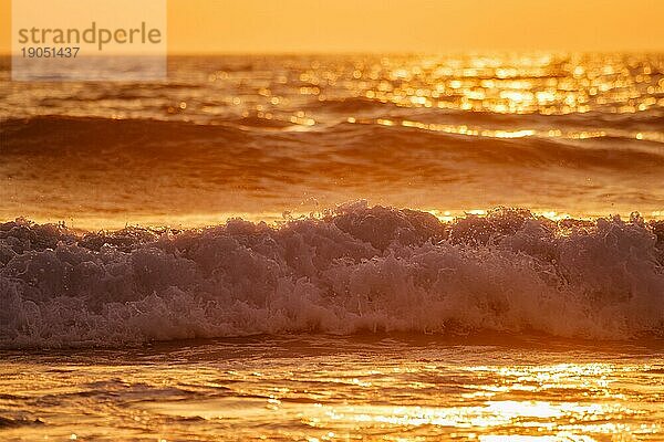 Brechende Meereswelle bei Sonnenuntergang im Gegenlicht der Sonne. Fonte da Telha  Costa da Caparica  Portugal  Europa