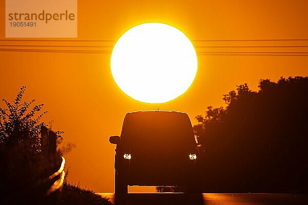 Ein Auto fährt bei Sonnenaufgang eine Landstraße bei Frankfurt am Main entlang.  Frankfurt am Main  Hessen  Deutschland  Europa