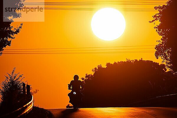 Ein Motorrad fährt bei Sonnenaufgang eine Landstraße bei Frankfurt am Main entlang.  Frankfurt am Main  Hessen  Deutschland  Europa