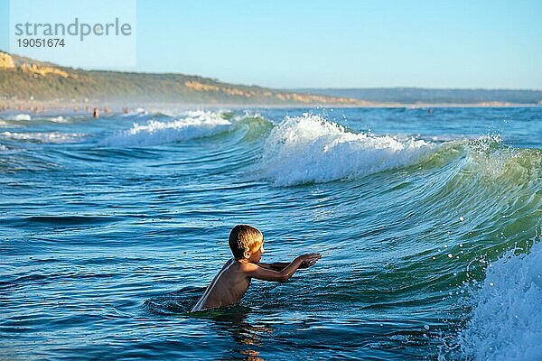 Junge hat Spaß genießt springt taucht in Ozean Meer Wellen des Atlantischen Ozeans. Strand Fonta da Telha  Costa da Caparica  Portugal  Europa