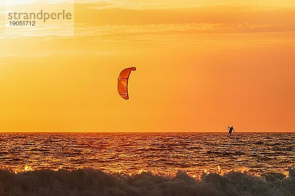 Foiling kiteboarding kitesurfing kiteboarder (kitesurfer) silhouette im Atlantik bei Sonnenuntergang. Strand Fonte da Telha  Costa da Caparica  Portugal  Europa