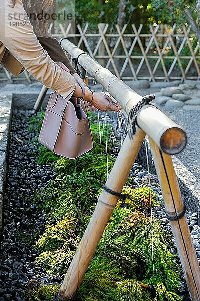 Frau hält ihre Hände zur rituellen Reinigung unter Wasser  Tsurugaoka Hachiman-g? Shinto-Schrein  Kamakura  Kanagawa Präfektur