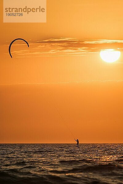 Foiling kiteboarding kitesurfing kiteboarder (kitesurfer) silhouette im Atlantik bei Sonnenuntergang. Strand Fonte da Telha  Costa da Caparica  Portugal  Europa