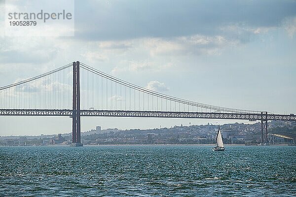 Blick auf die Brücke 25 de Abril  ein berühmtes touristisches Wahrzeichen Lissabons  die Lisboa und Almada über den Tejo verbindet  mit einem Touristenboot. Lissabon  Portugal  Europa