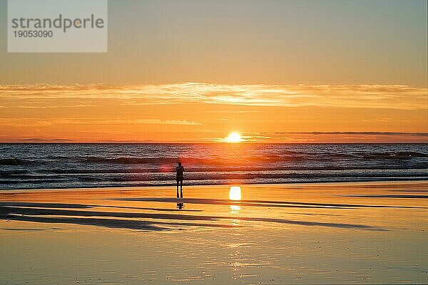 Sonnenuntergang über dem Atlantik mit der Silhouette eines Fotografen  der am Strand von Fonte da Telha  an der Costa da Caparica  Portugal  Bilder von der Brandung macht  Europa