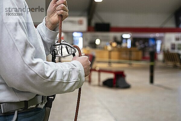 Eine Person hält ein Seil zur Sicherung in einer Kletterhalle