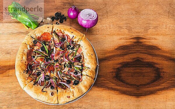 Ansicht einer Superpizza mit Gemüse auf einem hölzernen Hintergrund. Draufsicht auf Supreme Pizza mit Oliven und Gemüse auf Holztisch