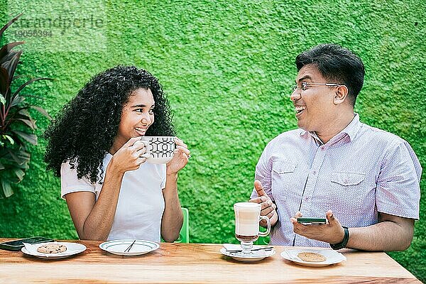Zwei glückliche Freunde  die einen Kaffee trinken und sich unterhalten. Mann und Frau unterhalten sich und genießen einen Kaffee in einer Cafeteria
