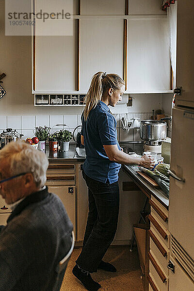 Seitenansicht einer Mitarbeiterin des Gesundheitswesens bei der Zubereitung von Kaffee in der Küche zu Hause