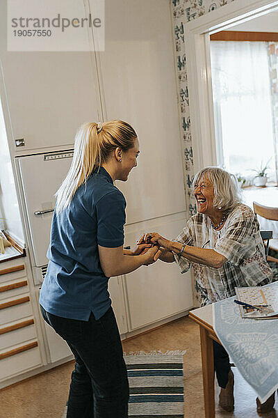Seitenansicht einer weiblichen Pflegekraft  die sich mit einer älteren Frau zu Hause unterhält
