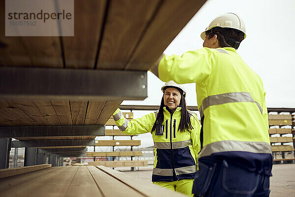 Eine lächelnde Arbeiterin prüft mit einem Kollegen in der Industrie die Bretter