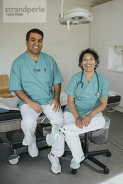 Porträt eines lächelnden Mannes und einer lächelnden Frau aus dem Gesundheitswesen  die im Krankenhaus sitzen