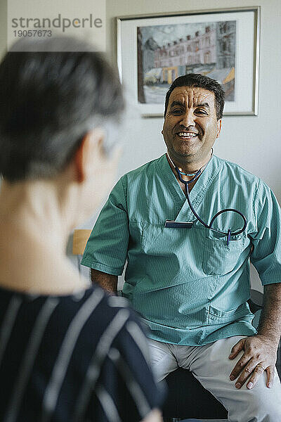 Glücklicher männlicher Arzt mit älterem Patienten in der Klinik