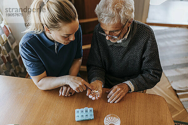 Hohe Winkel Ansicht der weiblichen Betreuerin erklärt Medizin Dosis zu älteren Mann zu Hause