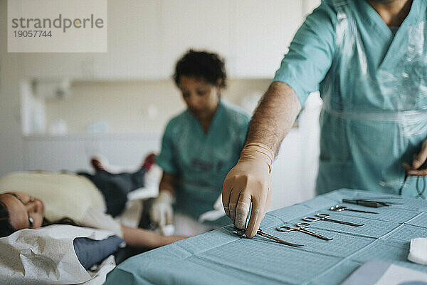 Männlicher Chirurg ordnet chirurgische Geräte auf einem Tisch im Krankenhaus an