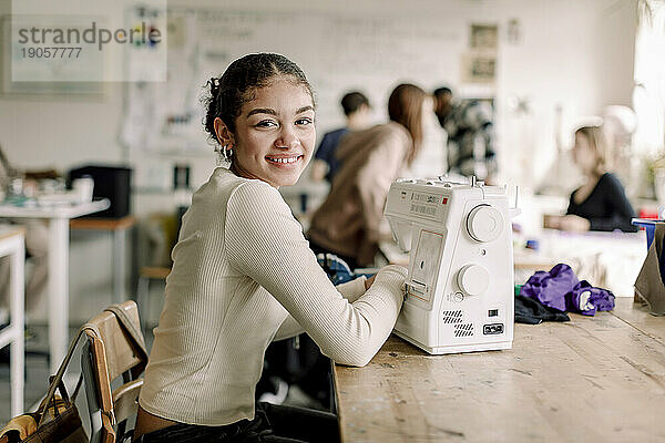 Seitenansicht Porträt von lächelnden Teenager-Mädchen mit Nähmaschine auf dem Schreibtisch in der High School