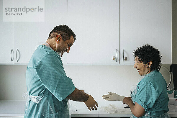 Glückliche Chirurginnen und Chirurgen tragen Handschuhe im Krankenhaus