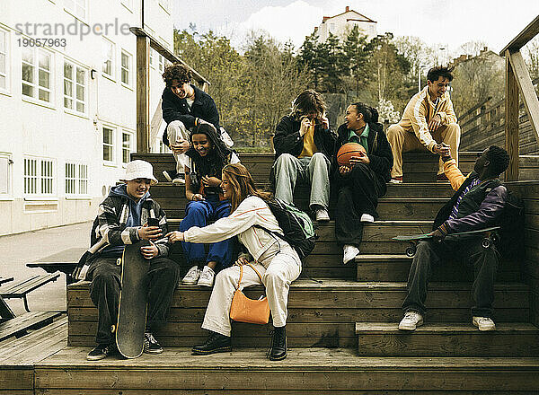 Glückliche männliche und weibliche Freunde  die Spaß haben  während sie auf Stufen sitzen