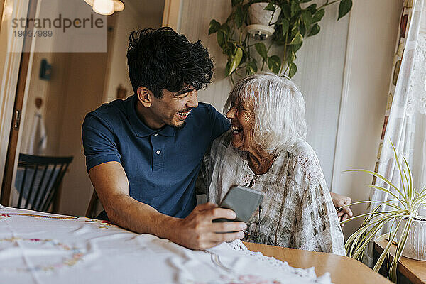 Glücklicher männlicher Pfleger mit lachender Seniorin zu Hause
