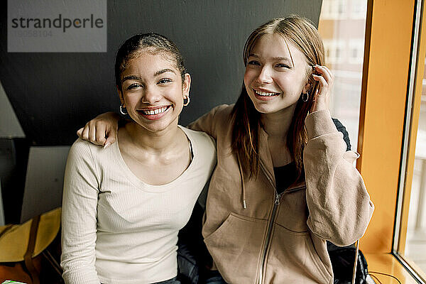 Porträt eines lächelnden Teenagers  der mit einer Freundin in der High School sitzt