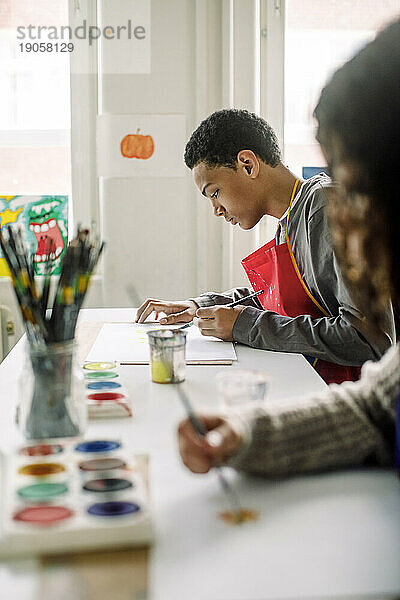 Seitenansicht eines männlichen Teenagers  der während des Kunstunterrichts in der High School malt