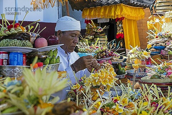 Balinesischer Mann bei der Vorbereitung von Speisegaben für eine traditionelle Hindu Zeremonie im Dorf Padang Bai  Padangbai  Padang Bay auf der Insel Bali  Indonesien  Asien