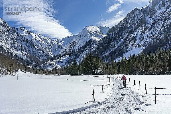 Nette Seniorin  die an einem sonnigen Wintertag in den Allgäuer Alpen bei Oberstdorf  Bayern  Deutschland ihr elektrisches Mountainbike fährt