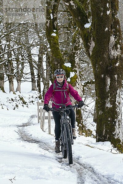 Nette Seniorin  die an einem sonnigen Wintertag in den Allgäuer Alpen bei Oberstdorf  Bayern  Deutschland ihr elektrisches Mountainbike fährt