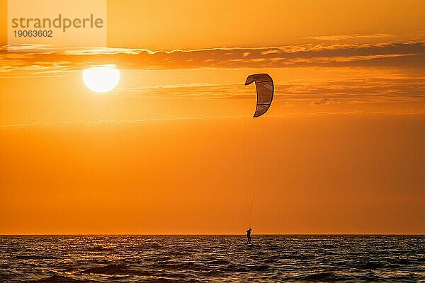 Foiling kiteboarding kitesurfing kiteboarder (kitesurfer) silhouette im Atlantik bei Sonnenuntergang. Strand Fonte da Telha  Costa da Caparica  Portugal  Europa