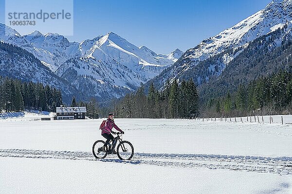 Nette ältere Frau auf ihrem elektrischen Mountainbike an einem sonnigen Wintertag in den Allgäuer Alpen bei Oberstdorf  Bayern  Deutschland  Europa