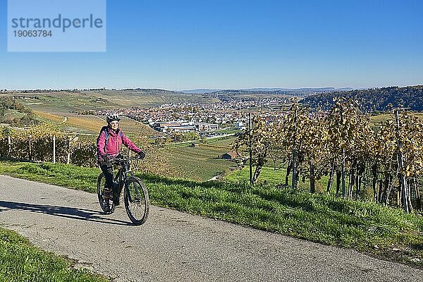 Nette Seniorin  die ihr elektrisches Mountainbike in den steilen  herbstlich gefärbten Weinbergen des Neckartals  Baden-Württemberg  Deutschland fährt