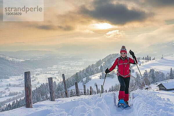 Schöne aktive Seniorin beim Schneeschuhwandern in den Allgäuer Alpen bei Oberstaufen mit Blick in den Bregenzerwald  Vorarlberg  Österreich  Europa