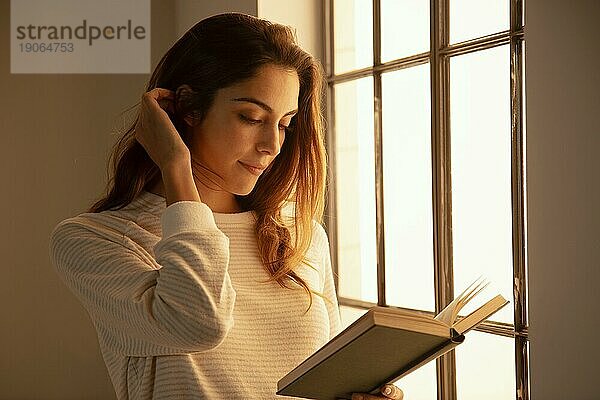 Seitenansicht junge Frau liest Buch zu Hause