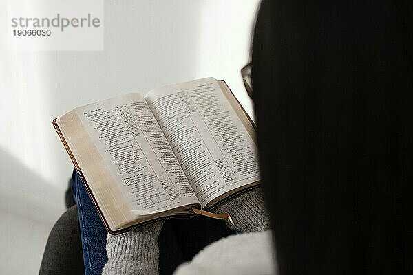 Frau liest Bibel in einem Haus