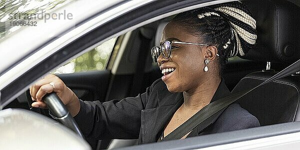 Seitenansicht einer glücklichen Frau  die ihr eigenes Auto fährt