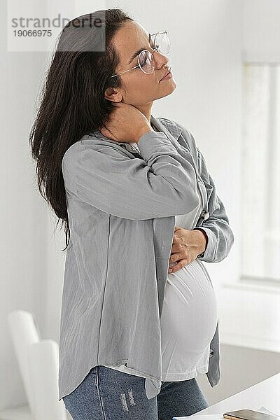 Seitenansicht schwangere Frau hält ihren Hals