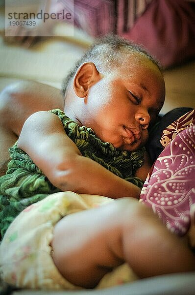 Palembe  Papua Neuguinea  Juli 2015: Kleines schlafendes Kind in den Armen seiner Mutter in Palembe  Sepik Fluss  Papua Neuguinea. Dokumentarischer Leitartikel
