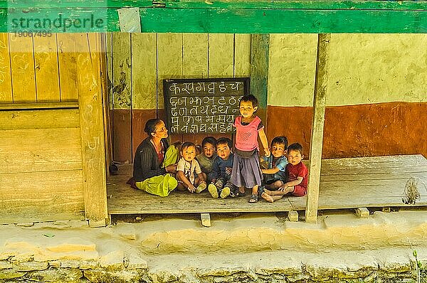 Kanchenjunga Trek  Nepal  etwa im Mai 2012: Kinder sitzen mit ihrer Lehrerin auf dem Boden und schauen in die Kamera in Kanchenjunga Trek  Nepal. Dokumentarischer Leitartikel  Asien