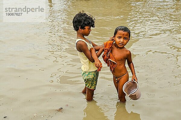 Sunderban  Bangladesch  etwa im Juli 2012: Zwei kleine Jungen mit schwarzen Haaren waschen sich im Fluss  ein Junge hält einen Eimer in Sunderban  Bangladesch. Dokumentarischer Leitartikel  Asien