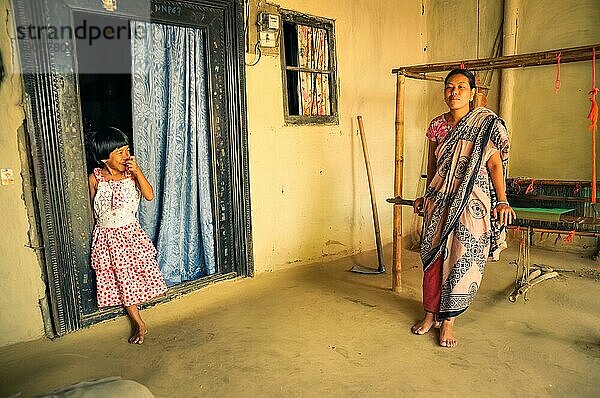 Srimongal  Bangladesch  etwa im Juli 2012: Einheimische Frau mit Kopftuch lehnt sich mit ihrer lächelnden Tochter in rotweißem Kleid in Srimongal  an einen Webstuhl. Dokumentarischer Leitartikel  Asien
