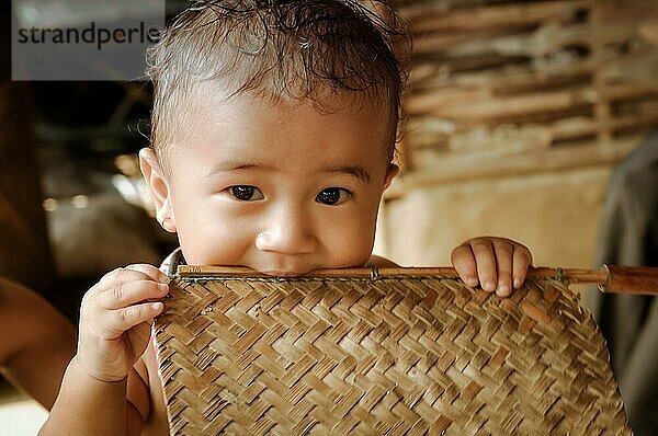 Damak  Nepal  ca. Mai 2012: Foto eines kleinen süßen Jungen  der in die Kamera schaut und einen Holzstock im Mund hält  im nepalesischen Flüchtlingslager in Damak  Nepal. Dokumentarischer Leitartikel  Asien