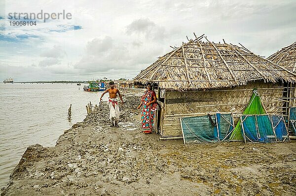 Sunderban  Bangladesch  etwa im Juli 2012: Frau und Mann stehen im Schlamm am Fluss vor ihrem einfachen Haus in Sunderban  Bangladesch. Dokumentarischer Leitartikel  Asien